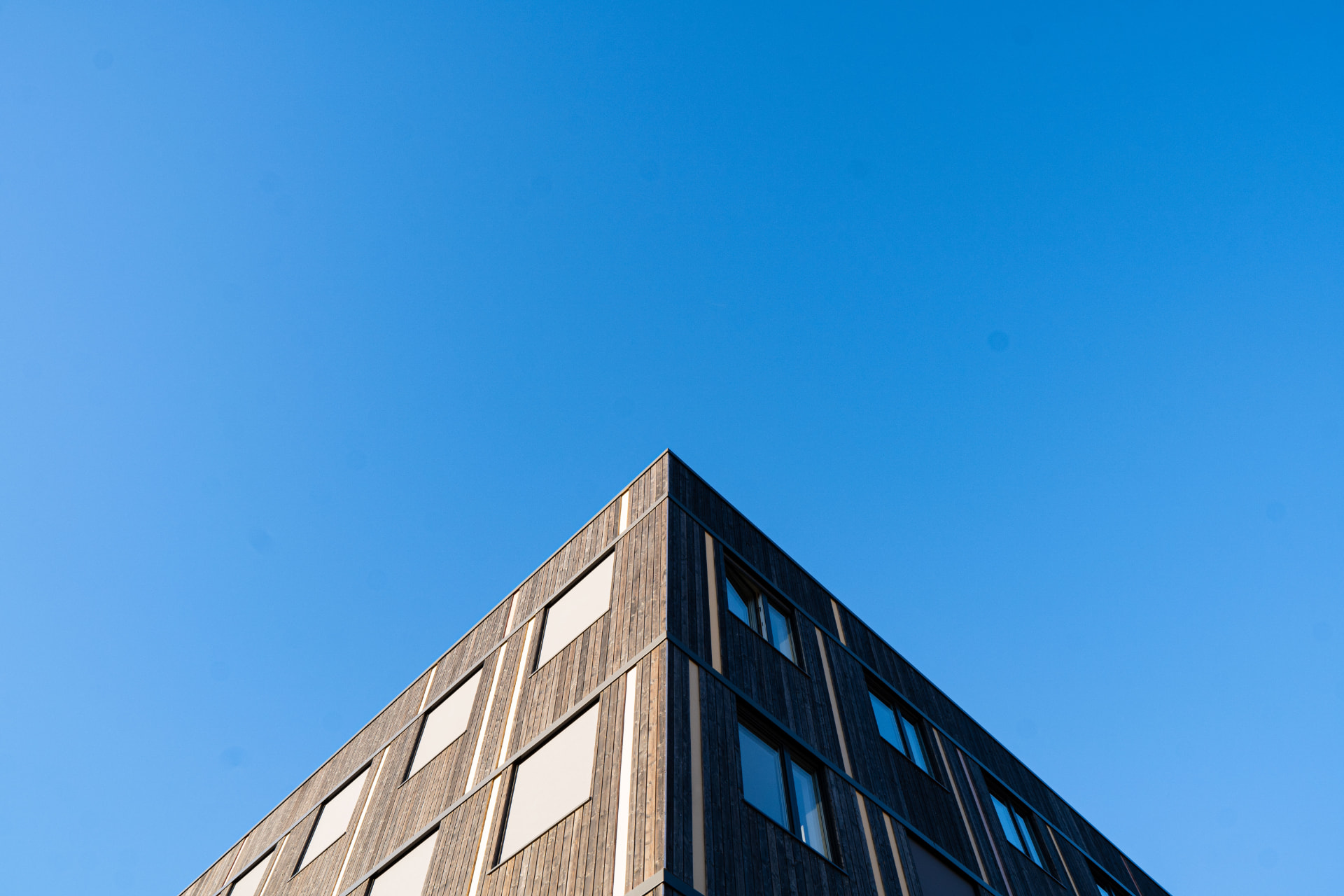 Modern timber building corner against a clear blue sky